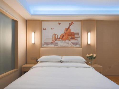 a bedroom with a large white bed and a picture of a violin at Vienna Hotel Zhejiang Tongxiang Puyuan in Jiaxing