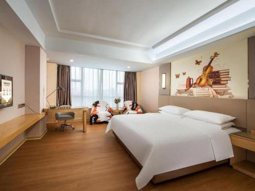 a bedroom with a large white bed and a desk at Venus International Hotel Guangdong Huizhou West Lake in Huizhou