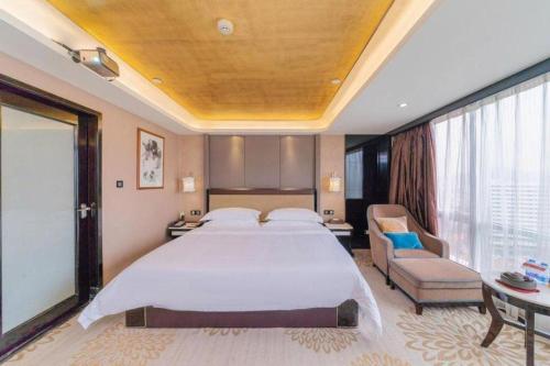 a bedroom with a large white bed and a chair at Venus Royal Hotel Guangdong Meizhou Huangjia Mingdian in Meizhou