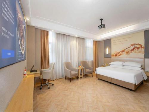 a hotel room with a bed and a table and chairs at Vienna Hotel Jiangsu Zhangjiagang Passenger Terminal Station in Zhangjiagang