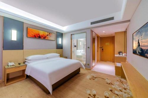 a bedroom with a large white bed and a bathroom at Vienna Hotel Guangdong Zhongshan Xiaolan High-Speed Railway Station in Zhongshan