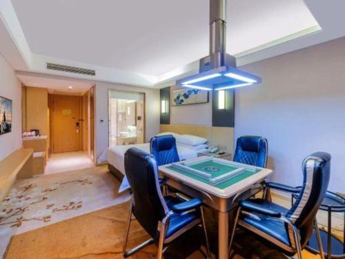 a room with a table and chairs and a bed at Vienna Hotel Guangdong Zhongshan Xiaolan High-Speed Railway Station in Zhongshan