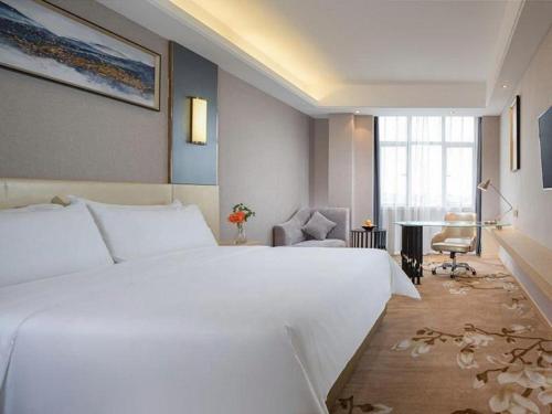 a bedroom with a large white bed and a desk at Vienna Hotel Guangdong Zhongshan Xiaolan High-Speed Railway Station in Zhongshan