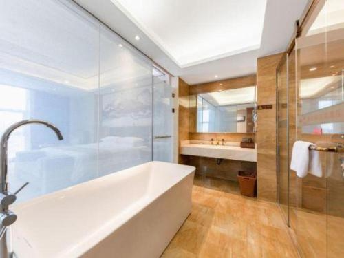 a bathroom with a tub and a shower and a sink at Venus Royal Hotel Nanning East High-Speed Railway Station in Nanning