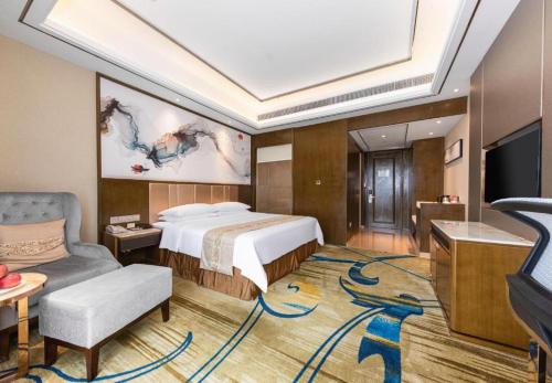 a bedroom with a bed and a tv and a couch at Venus Royal Hotel Nanning East High-Speed Railway Station in Nanning