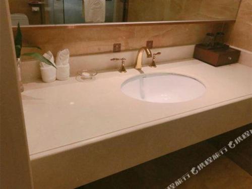 a bathroom sink with a gold faucet at Venus Royal Hotel Nanning East High-Speed Railway Station in Nanning