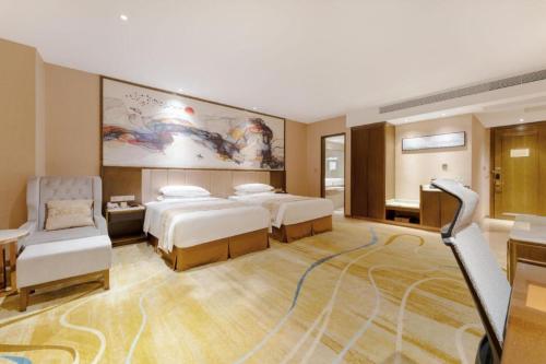 a hotel room with two beds and a couch at Venus Royal Hotel Nanning East High-Speed Railway Station in Nanning