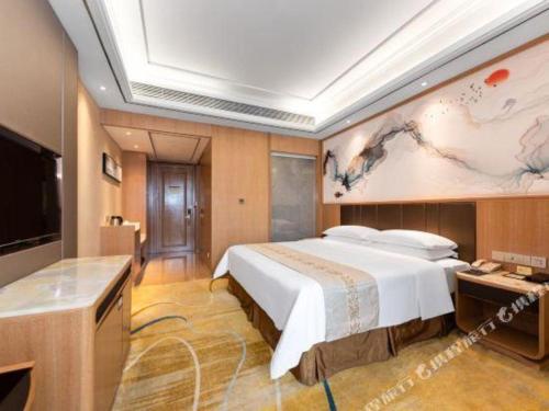 a bedroom with a large bed and a tv at Venus Royal Hotel Nanning East High-Speed Railway Station in Nanning