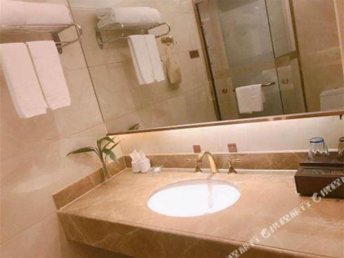 a bathroom with a sink and a large mirror at Venus Royal Hotel Nanning East High-Speed Railway Station in Nanning