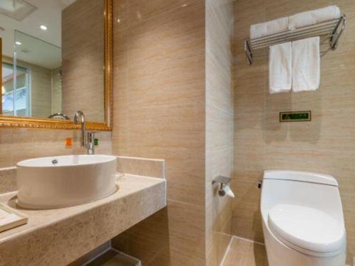 une salle de bain avec un lavabo, des toilettes et un miroir dans l'établissement Vienna Hotel Nanchang New Grand Hongcheng Market Xianghu 1st Hospital, à Nanchang