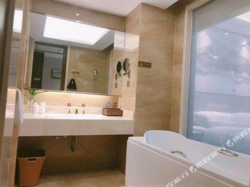 a bathroom with a sink and a mirror and a tub at Venus Royal Hotel Nanning East High-Speed Railway Station in Nanning