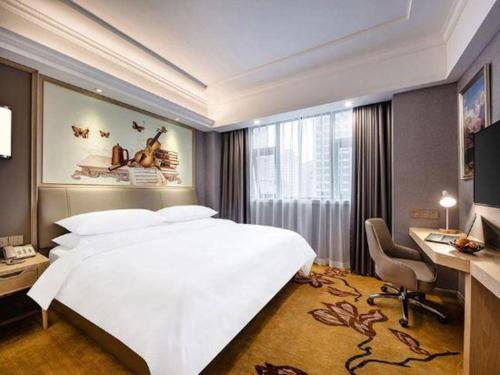 a bedroom with a large white bed and a desk at Vienna Hotel Zhejiang Lishui Qingtian Post Building in Lishui