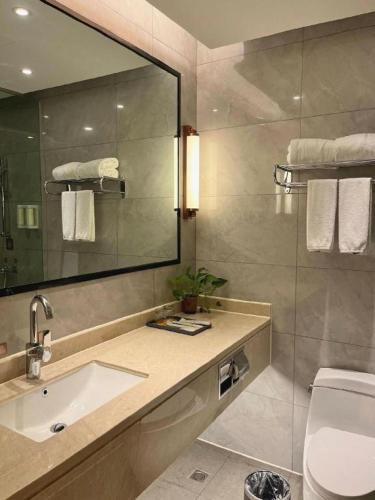 a bathroom with a sink and a mirror and a toilet at Vienna Hotel Jiangxi Shangrao High-Speed Railway Station in Shangrao