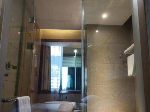 a bathroom with a sink and a shower with a mirror at Vienna Hotel Zhejiang Lishui Qingtian Post Building in Lishui