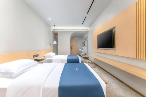 a bedroom with two beds and a flat screen tv at Borrman Hotel Jining High-tech Huangtun in Jining