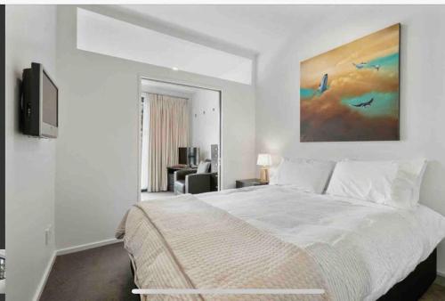 a white bedroom with a bed and a tv at CBD Apartment in Wellington
