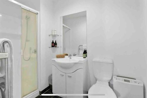 a white bathroom with a toilet and a sink at CBD Apartment in Wellington