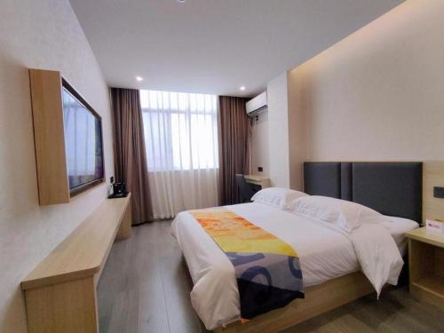 a bedroom with a large bed and a television at Shell Hotel Wuxi Huishan District Chang'an Town in Wuxi