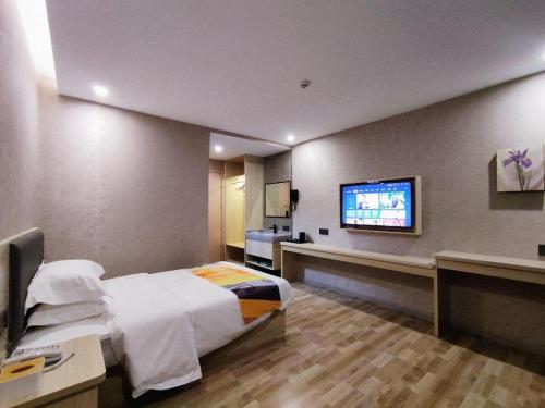 a hotel room with a bed and a flat screen tv at Shell Hotel Wuxi Huishan District Chang'an Town in Wuxi