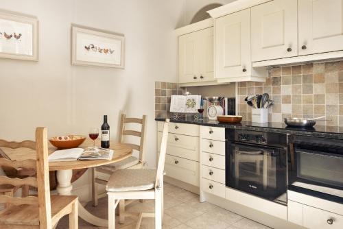 a kitchen with white cabinets and a wooden table and a tableablish at Wetherlam in Ambleside
