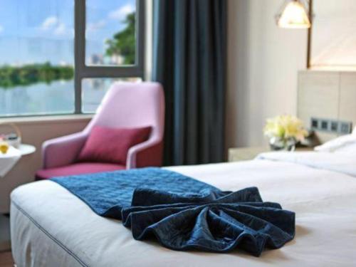 a hotel room with a bed and a pink chair at Xiamen Seashine Lakeview Hotel in Xiamen