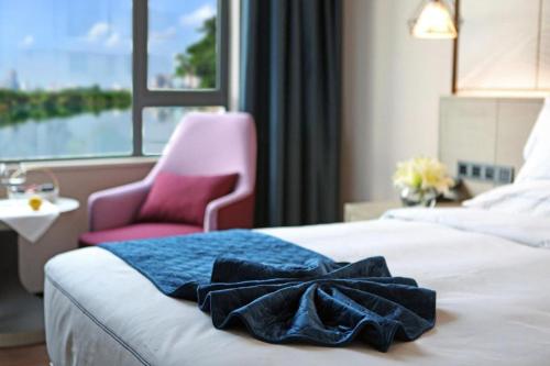 a hotel room with a bed and a pink chair at Xiamen Seashine Lakeview Hotel in Xiamen