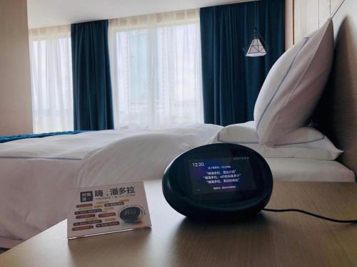 a clock on a table next to a bed at Xiamen Seashine Lakeview Hotel in Xiamen