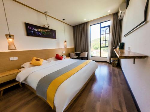 a hotel room with a large bed and a desk at Furong Town 373 Jingjingjia Inn in Wang-ts'un