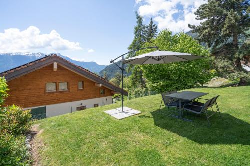 a table and an umbrella in the yard of a house at 2,5 Plein Sud avec terrasse in Ovronnaz