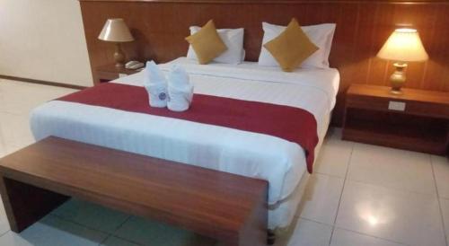 a hotel room with a large bed and a table at Garuda Hotel Pontianak in Pontianak