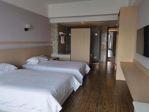 a hotel room with two beds and a television at Grand Nest Hotel (Tang Jia Wan Beach) in Zhuhai