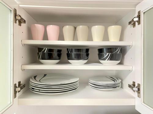 a cupboard filled with plates and bowls and dishes at サニーサイドホステル1号館 in Uji