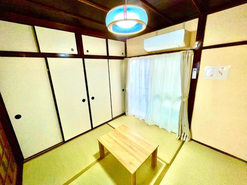 a room with a bench and a window and cabinets at サニーサイドホステル1号館 in Uji