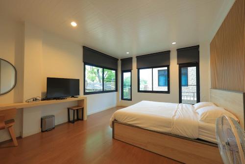 a bedroom with a bed and a desk with a television at Phu Plearn Ta Pool Villas Khaoyai in Ban Bung Toei