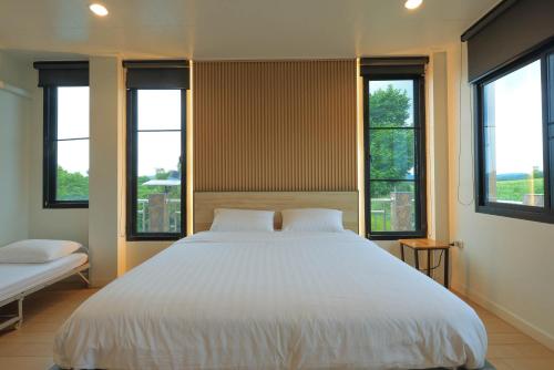 a bedroom with a large white bed with windows at Phu Plearn Ta Pool Villas Khaoyai in Ban Bung Toei