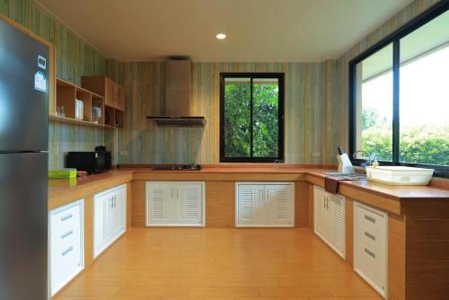 a large kitchen with white cabinets and a window at Phu Plearn Ta Pool Villas Khaoyai in Ban Bung Toei