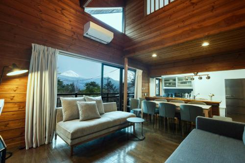 a living room with a couch and a table with chairs at Lake England 富士山が見える隠れ家ロッジ in Fujikawaguchiko