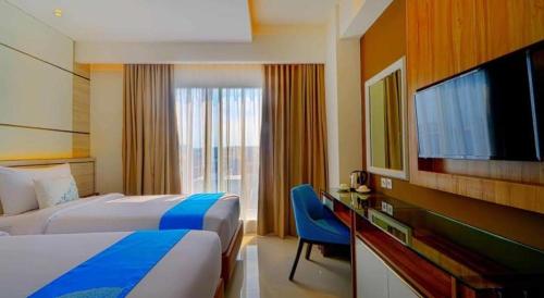 a hotel room with a bed and a flat screen tv at Java Lotus Hotel Jember in Jember