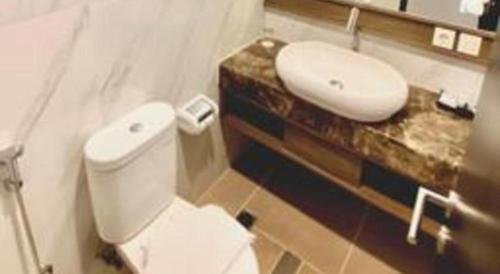 a bathroom with a white toilet and a sink at Java Lotus Hotel Jember in Jember
