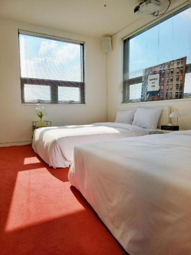 two beds in a room with two large windows at CS Premier Hotel in Seoul