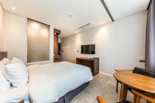 a bedroom with a white bed and a table at CS Premier Hotel in Seoul