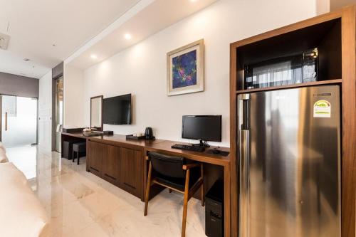 a room with a desk with two monitors and a refrigerator at CS Premier Hotel in Seoul