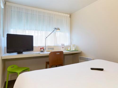 a room with a desk with a computer and a monitor at Campanile Pont-à-Mousson in Pont-à-Mousson