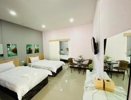 a bedroom with two beds and a table and chairs at Sweet Hug Hotel in Suphan Buri