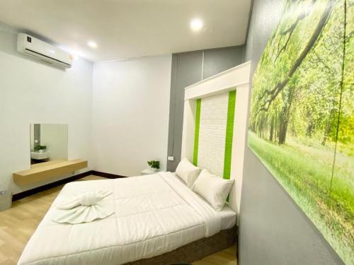a bedroom with a white bed and a painting on the wall at Sweet Hug Hotel in Suphan Buri