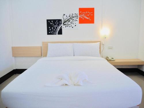 a white bed with a white towel on top of it at Sweet Hug Hotel in Suphan Buri