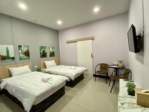a bedroom with two beds and a table and a tv at Sweet Hug Hotel in Suphan Buri