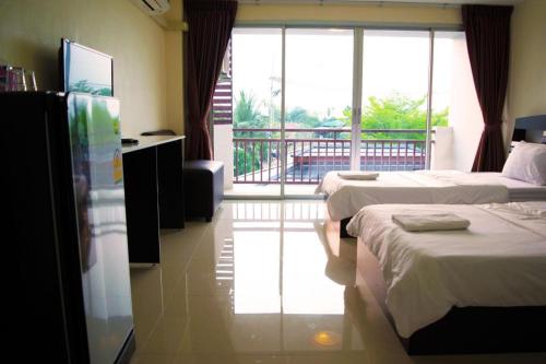 a hotel room with two beds and a balcony at Nantharom Hotel and Restaurant in Chachoengsao