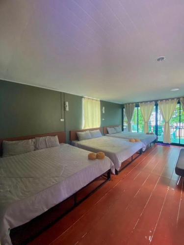 two beds in a large room with windows at Hat yao Seaview Beach Room in Trang