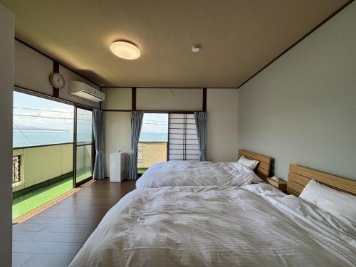 a bedroom with two beds and a large window at お宿UmiSora in Kami Amakusa